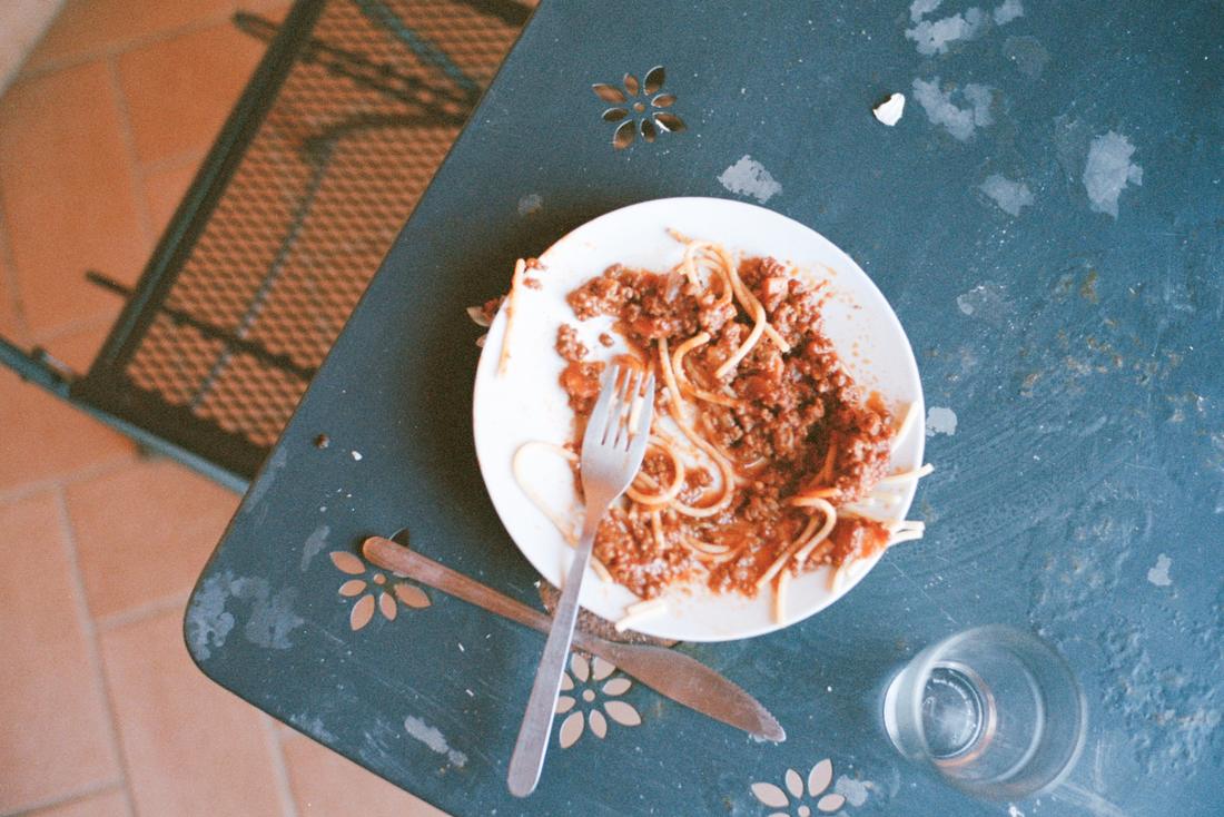 En nästan uppäten tallrik spaghetti på ett blått bord