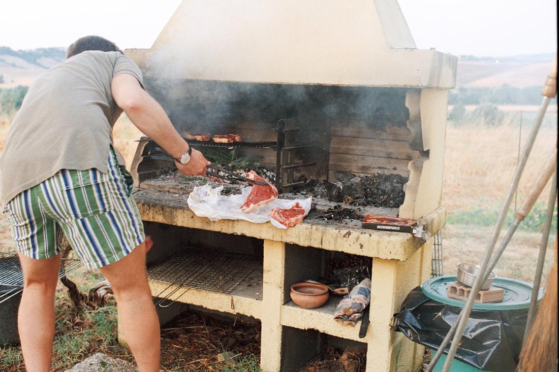 Någon grillar biffar på en stor utomhusgrill